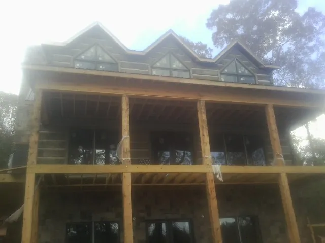 Dormers and porch framing on a large log home under construction — Roof Coating work by our crew in Loyalhanna