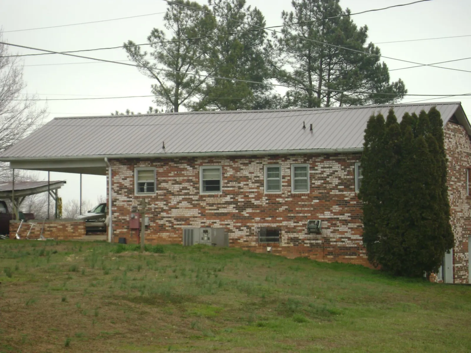 Gray metal roof on a brick split level home with a carport in Loyalhanna