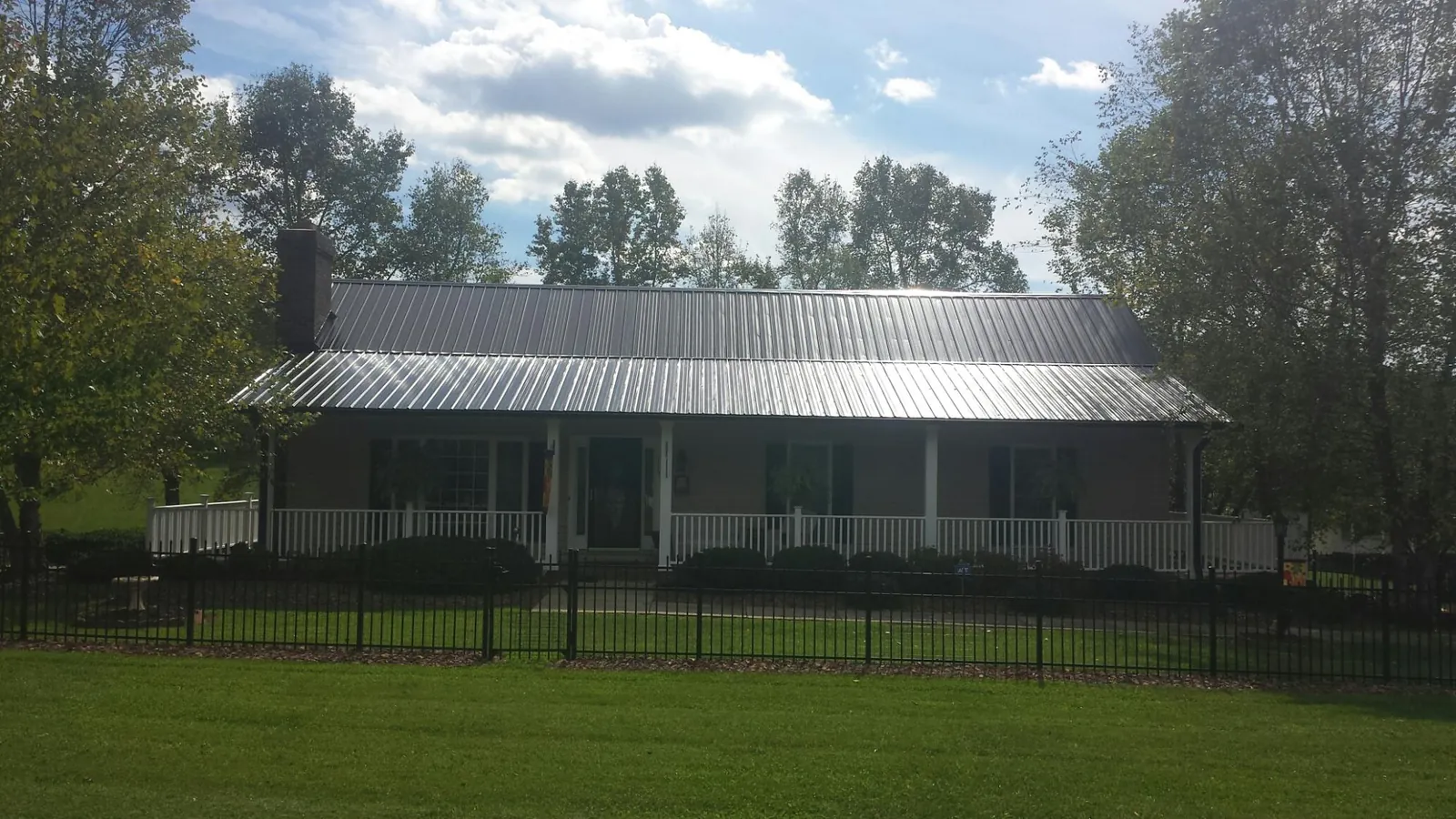 Gray metal roof on a brick ranch with a full width front porch — Gutter Guard Installation work by our crew in Loyalhanna