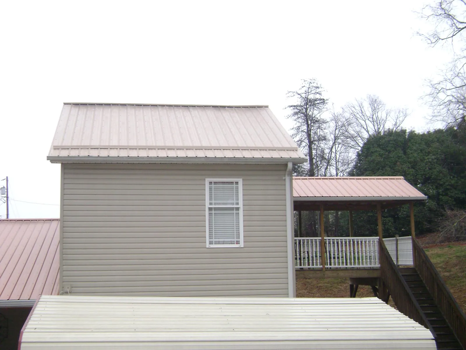Tan metal roofs on a two story addition and attached porch, from a Roof Replacement job in Loyalhanna