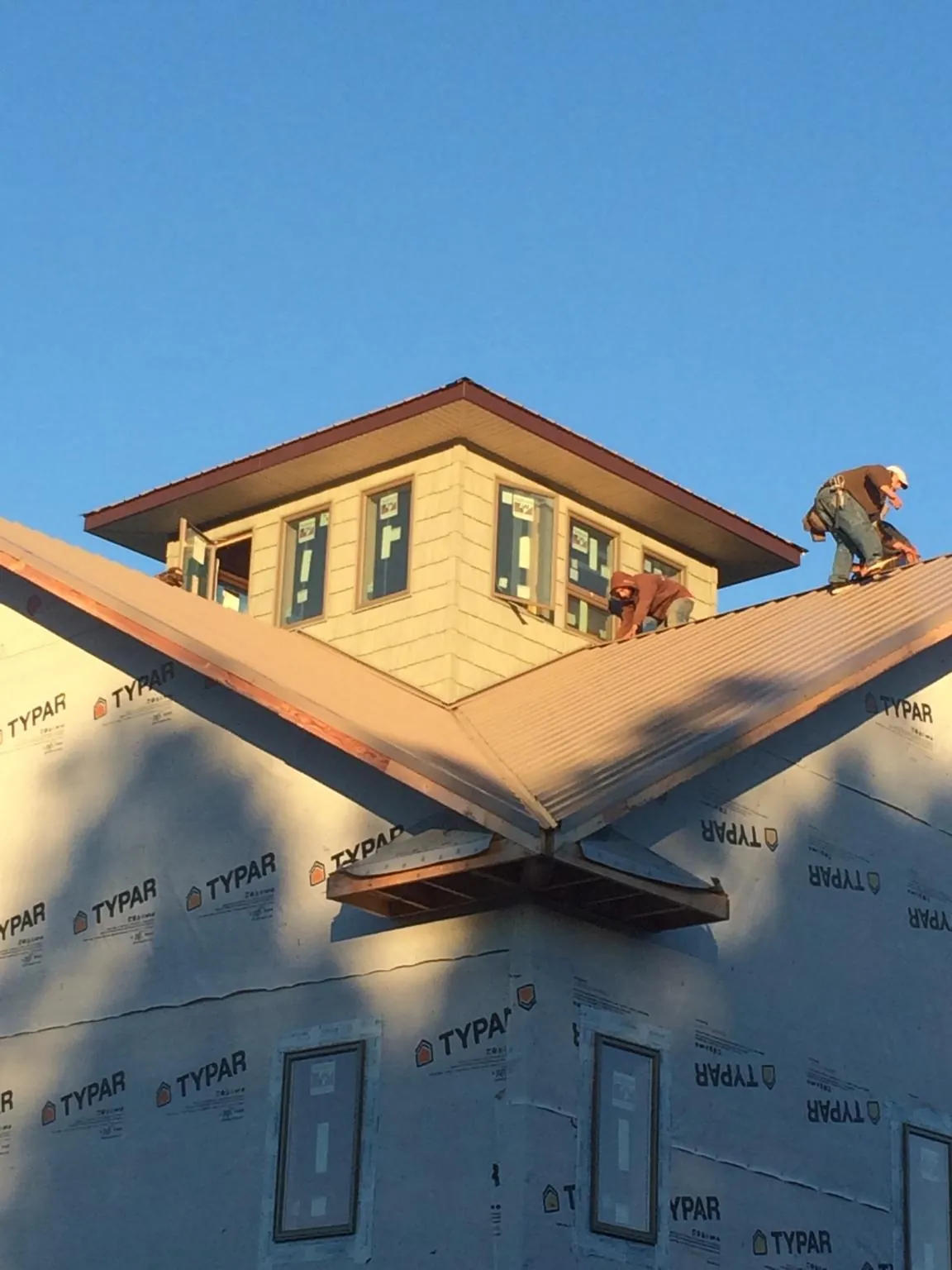 Roofers working around a rooftop cupola on a new metal roof at sunset — Roof Waterproofing in Loyalhanna by Roofing Brothers